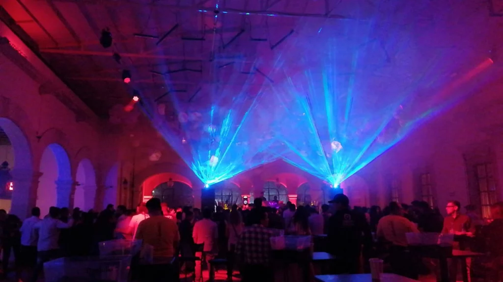 Salón de eventos decorado con luces láser y efectos visuales durante una presentación.