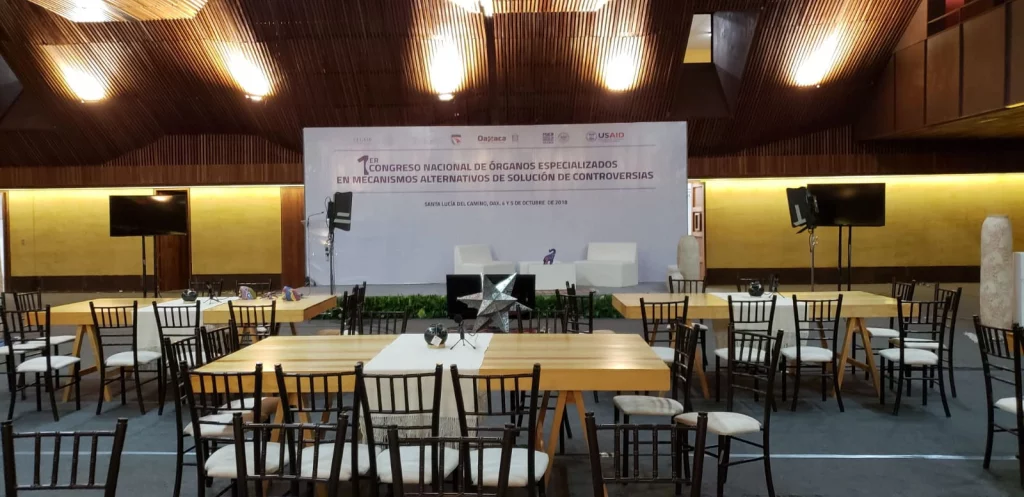 Escenario con ponentes y asistentes en un foro corporativo con decoración profesional.