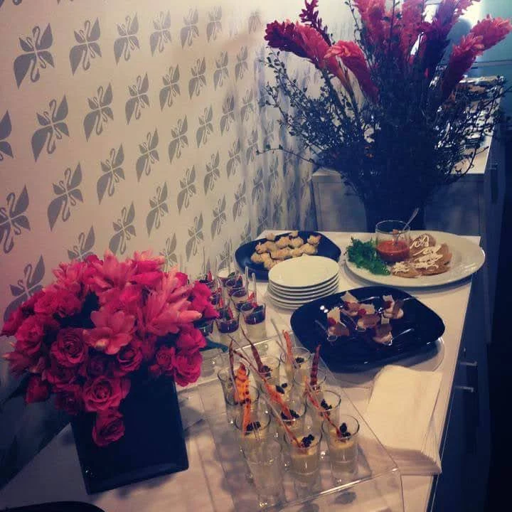 Mesa con aperitivos y flores frescas decorando un evento corporativo.