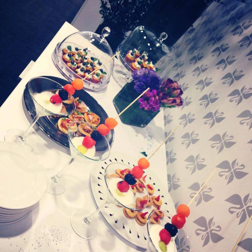 Mesa de postres con decoración floral y alimentos servidos en recipientes de vidrio.