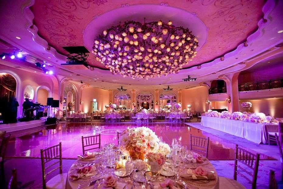 Mesa decorada con arreglos florales y lámpara de techo elaborada en un salón de eventos.