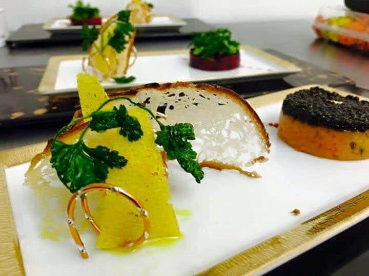 Platos decorados con ingredientes frescos y detalles artísticos en un evento corporativo.