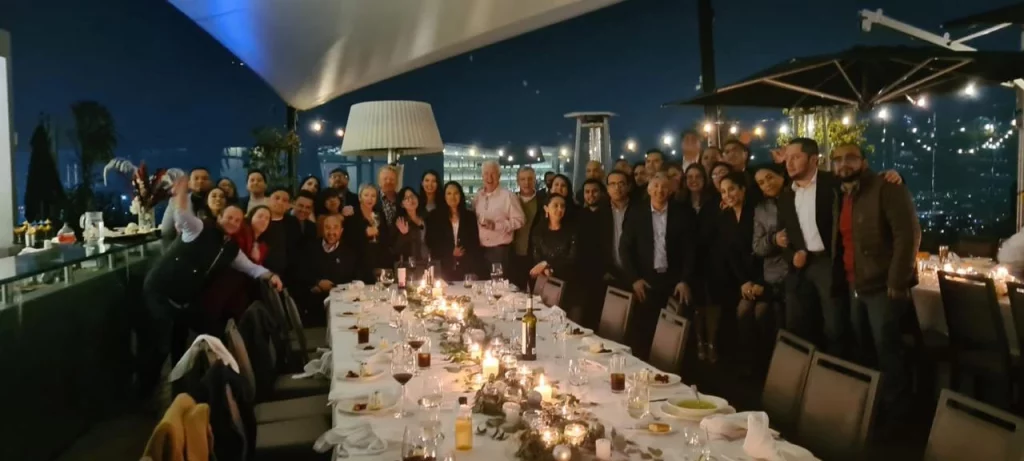  Grupo de empleados posando en una cena corporativa al aire libre con iluminación tenue.