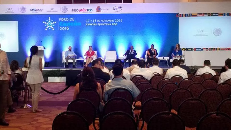 Panelistas discutiendo en un foro empresarial con asistentes sentados en filas.